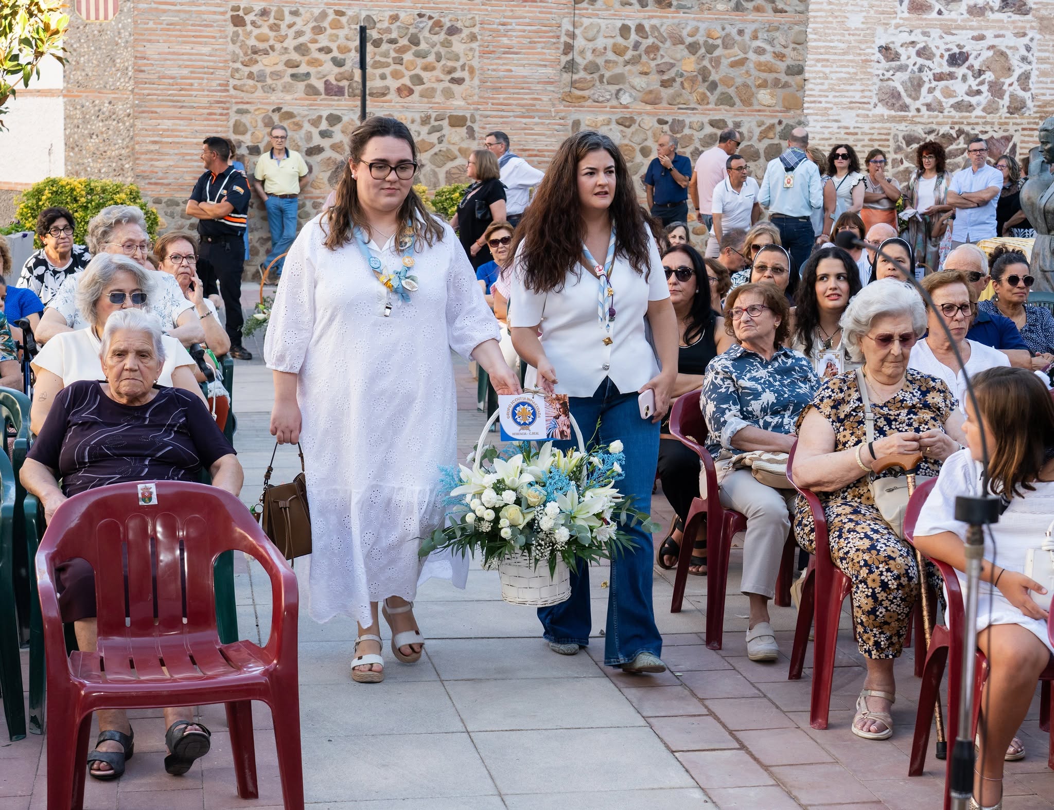 Dos mujeres avanzan por el pasillo central con un ramo de flores